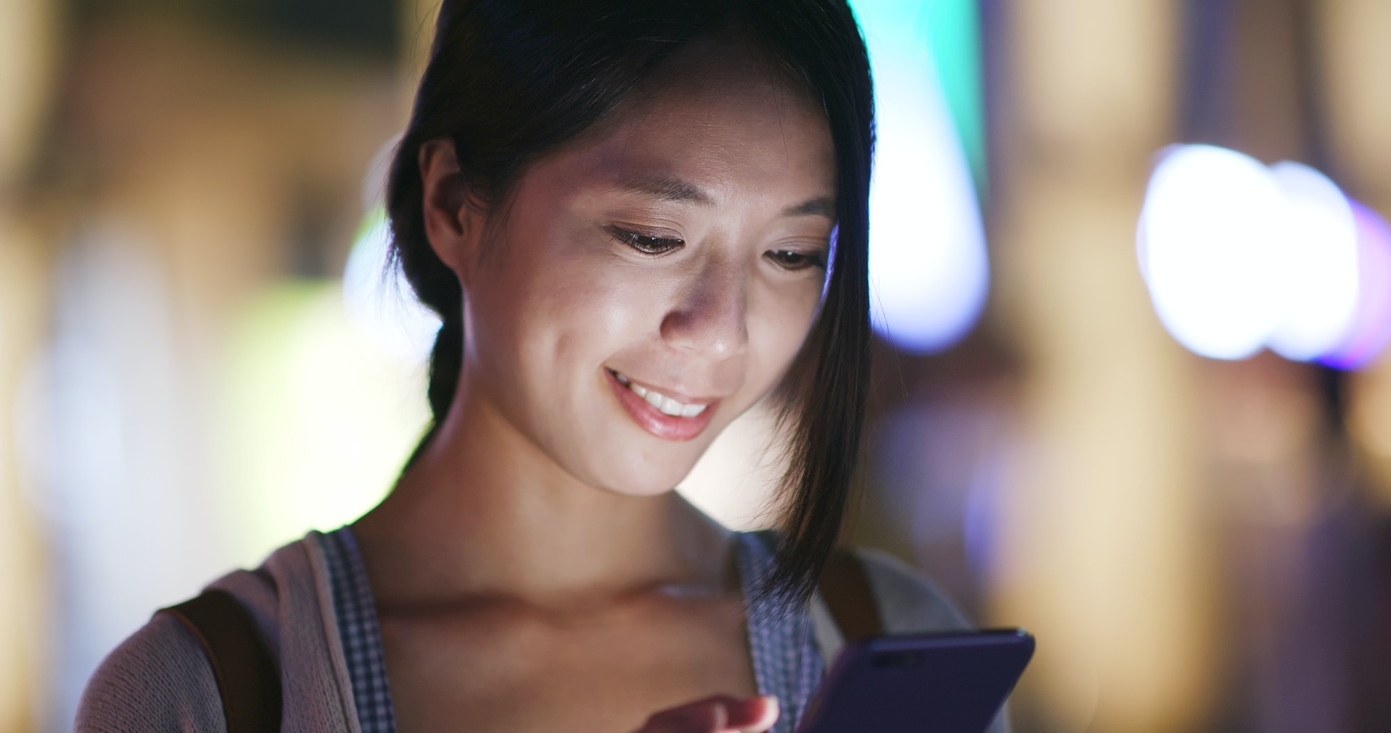 Woman use of smartphone in the city at night